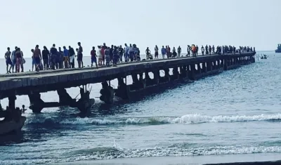 Grupo de personas exponiendo sus vidas encima de lo que queda del muelle.