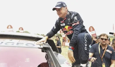 Carlos Saiz sube al techo de su vehículo para festejar su triunfo. 