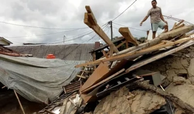 Un hombre subido en lo alto de su casa derrumbada en la localidad de Megamendung, en Bogor (Indonesia)