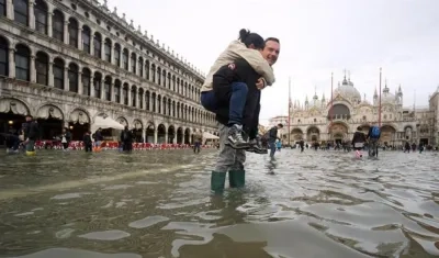 Un hombre carga a sus espaldas con su hija en la Plaza de San Marco, inundada como consecuencia del temporal de lluvia registrado en Venecia, Italia.