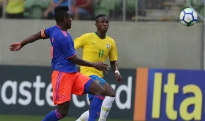 Vinicius Jr (d) de Brasil disputa un balón con Yeller Goez.