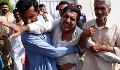 Dos hombres consuelan al familiar de una víctima tras el ataque perpetrado contra el consulado de China en Karachi, Pakistán.