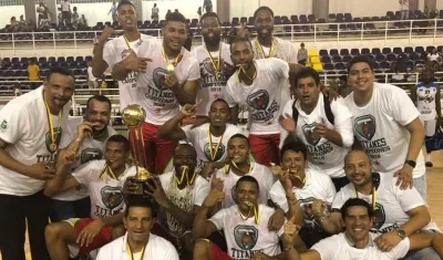 Xavier Roberson sostiene el trofeo de campeón mientras que sus compañeros celebran el título.