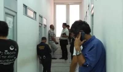 El taxista, al fondo, recostado sobre la pared.