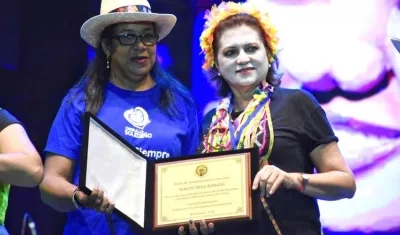 La Gerente de la empresa Carnaval, Carla Celia, entregando el reconocimiento a la hija de Efrain Mejía.