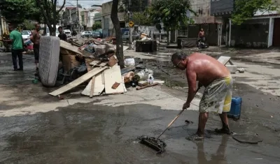 Un hombre limpia una calle afectada por las inundaciones.