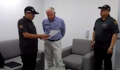 Los agentes del CTI Bogotá, leyéndole los derechos del capturado al exgerente de la Triple A Ramón Navarro.