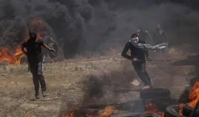 Dos palestinos corren en busca de refugio durante los enfrentamientos surgidos tras las protestas convocadas cerca de la frontera con Israel en el este de la franja de Gaza.