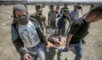 Varios manifestantes trasladaban ayer a un joven herido durante las protestas en la frontera de Gaza e Israel.