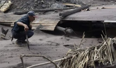 Un hombre observa los daños a una vivienda afectada por el volcán de Fuego.