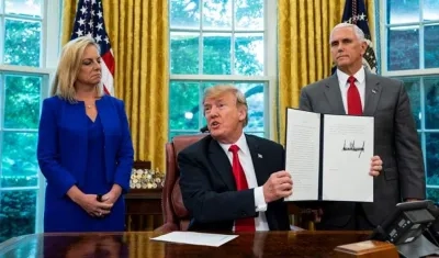 El presidente estadounidense, Donald Trump (c) muestra la orden ejecutiva para detener la separación de los niños inmigrantes de sus padres. 