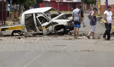 Ciudadanos pasan frente a un coche quemado, en la ciudad de Masaya