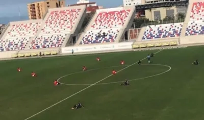 Jugadores del Barranquilla FC y del Deportivo Pereira se sientan en la cancha. 