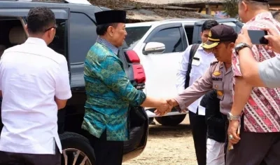 El ministro de seguridad indonesio Wiranto (de verde) es recibido por un oficial local poco antes de ser atacado por un hombre con un cuchillo.
