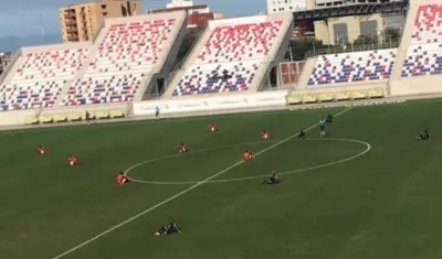Jugadores del Barranquilla FC y del Deportivo Pereira se sientan en la cancha.