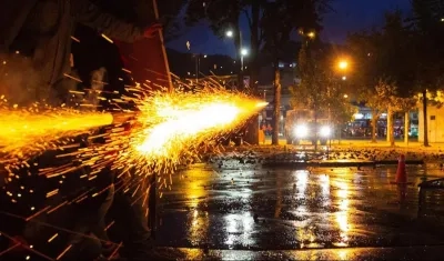 Manifestantes lanzan un artefacto contra una tanqueta de la Policía esta noche en Bogotá.