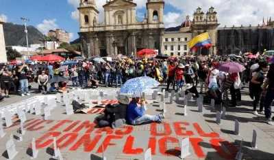 Dos personas permanecen sentadas en medio de una instalación con nombres de víctimas del conflicto armado colombiano