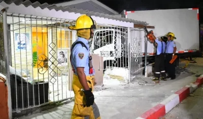 Bomberos trabajan en la extracción del camión que quedó aprisionado entre las rejas de la casa.