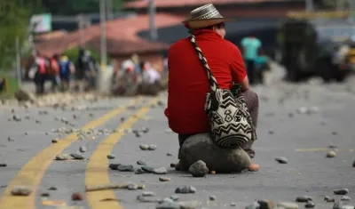 Indígena espera sobre una roca durante el bloqueo de la vía Panamericana en el municipio de Caldono, Cauca