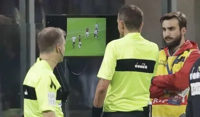Árbitros observan una jugada repetida en el sistema del VAR. 