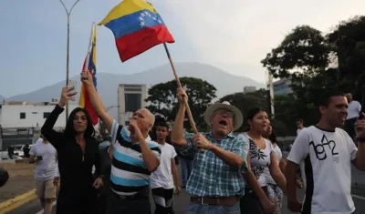 Simpatizantes del presidente interino Juan Guaidó ondean banderas este martes en la base militar La Carlota, donde se encuentra el presidente interino Guaidó y un grupo de militares que le apoyan. 