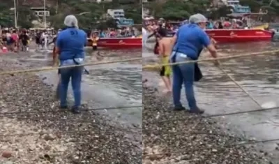 Una mujer lava un trapero en la bahía de Taganga.