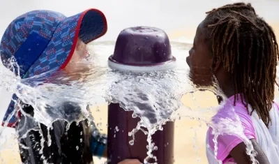 Niñas se refrescan en una fuente en Estados Unidos.