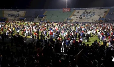 Aficionados ingresan al campo y se protegen de los gases lacrimógenos lanzados por las autoridade