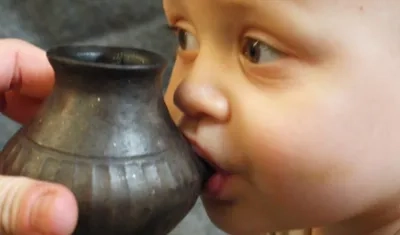 Bebé actual alimentado a partir de un recipiente reconstruido a semejanza del que se describe en el estudio de Nature.