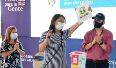 Una beneficiaria exhibiendo el título de vivienda,