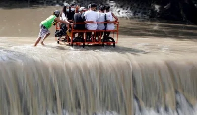 Varios lugareños cruzan en una carreta una presa desbordada en la frontera entre la provincia de Cavite y la ciudad de Las Piñas, en Filipinas, este domingo.