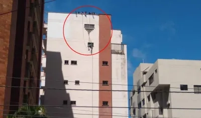 Los dos obreros colgando tras reventársele la guaya del andamio.