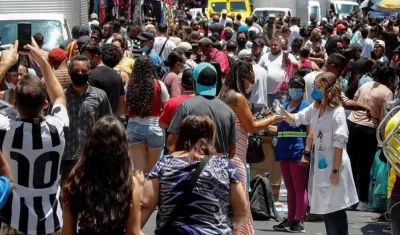 Una enfermera desinfecta las manos de las personas que caminan en una concurrida vía comercial hoy, en el centro de Sao Paulo (Brasil).