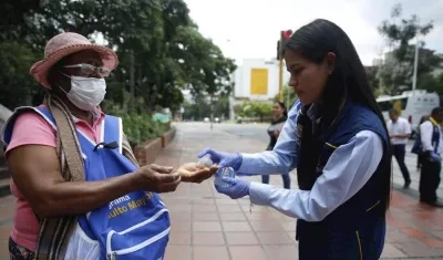Una joven le suministra gel antibacterial a una adulta mayor en Cali.