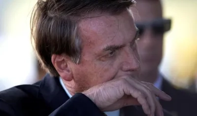 Jair Bolsanoro, presidente de Brasil, tocándose la cara con las manos en tiempos de coronavirus.