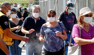 Las autoridades realizan desinfección de las manos a personas que hacen filas en Chile.