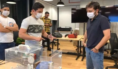 Jóvenes innovadores y alcalde muestran un equipo de ventilación mecánica.
