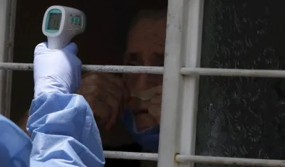 Una enfermera toma la temperatura de un adulto mayor.