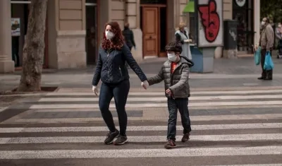 Una mujer acompañada de un niño cruza una calle en Valencia. 