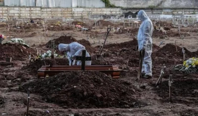 Empleados de una funeraria realizan el entierro de una persona que falleció a causa del Covid-19 en el cementerio de Caju, en la zona norte de Río de Janeiro.