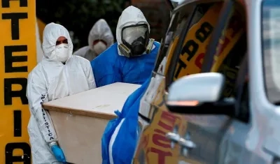 Personal policial y de una funeraria de Quito, retiran el cadáver de una anciana de 91 años que falleció por Covid-19, en un barrio periférico de Quito (Ecuador).