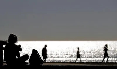 Varias personas disfrutan de un paseo a primera hora en la playa de la Malvarrosa, en Valencia.
