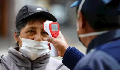 Una mujer con tapabocas le miden la temperatura antes subir a un transporte público.