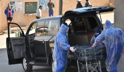 Empleados de una funeraria retiran el cuerpo sin vida de un hombre que permaneció durante horas abandonado en una calle, este domingo en Cochabamba.