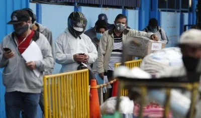 Un grupo de personas espera embarcarse en un bus interprovincial en un terminal, en Lima (Perú).