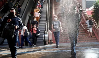Usuarios pasan por una cabina de desinfección mientras salen de una estación del metro, en el centro de la ciudad de Osasco, en Sao Paulo (Brasil). 
