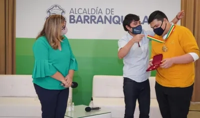 Alcalde Pumarejo condecora al estudiante Alejandro Salas por su puntaje perfecto de las Pruebas Saber 11. Observa la secretaria de educación, Bibiana Rincón.