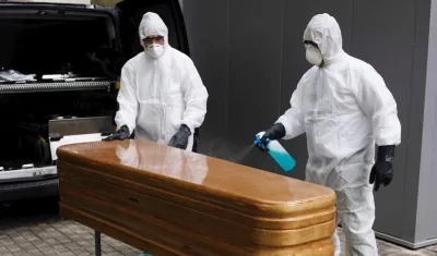 Trabajadores de un tanatorio sacan del hospital un ataúd para proceder a su desinfección antes de trasladarlo al cementerio. 