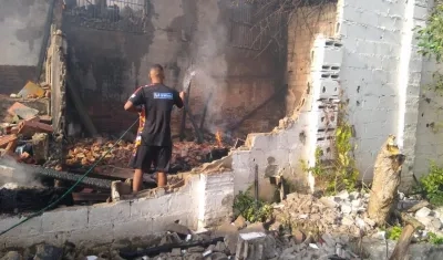 Una persona riega agua en el lugar para evitar que el fuego vuelva a a surgir. 