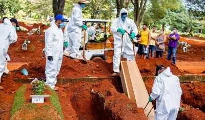 Empleados del servicio funerario entierran a una víctima de la covid-19, en el cementerio de Vila Formosa, en São Paulo (Brasil).
